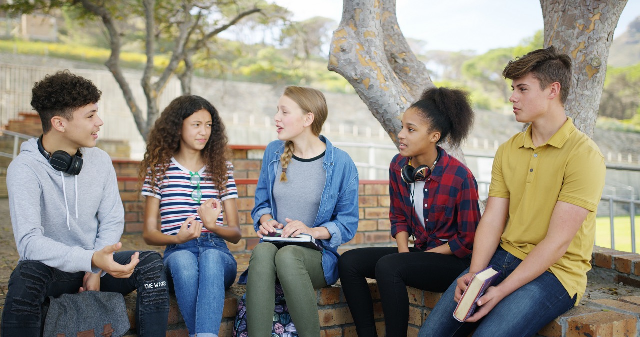 High school, students and talking outdoor for learning, education and conversation for knowledge. Teen, boys and group of girls with scholarship discussion, exam and study tips for test with friends.