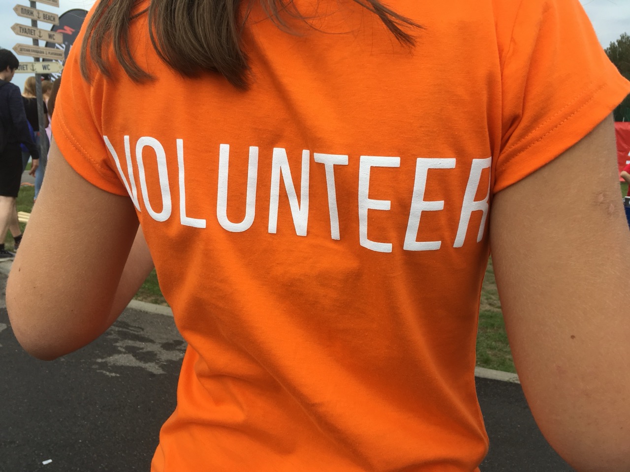Volunteer girl in orange t-shirt rear view